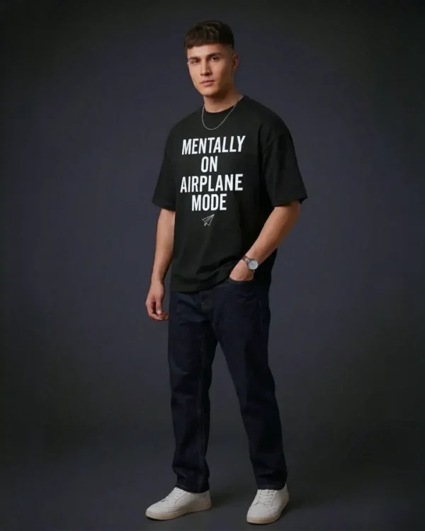 Male model in a three-quarter pose, showcasing the shoulder drop of the black t shirt oversized and the paper plane graphic.